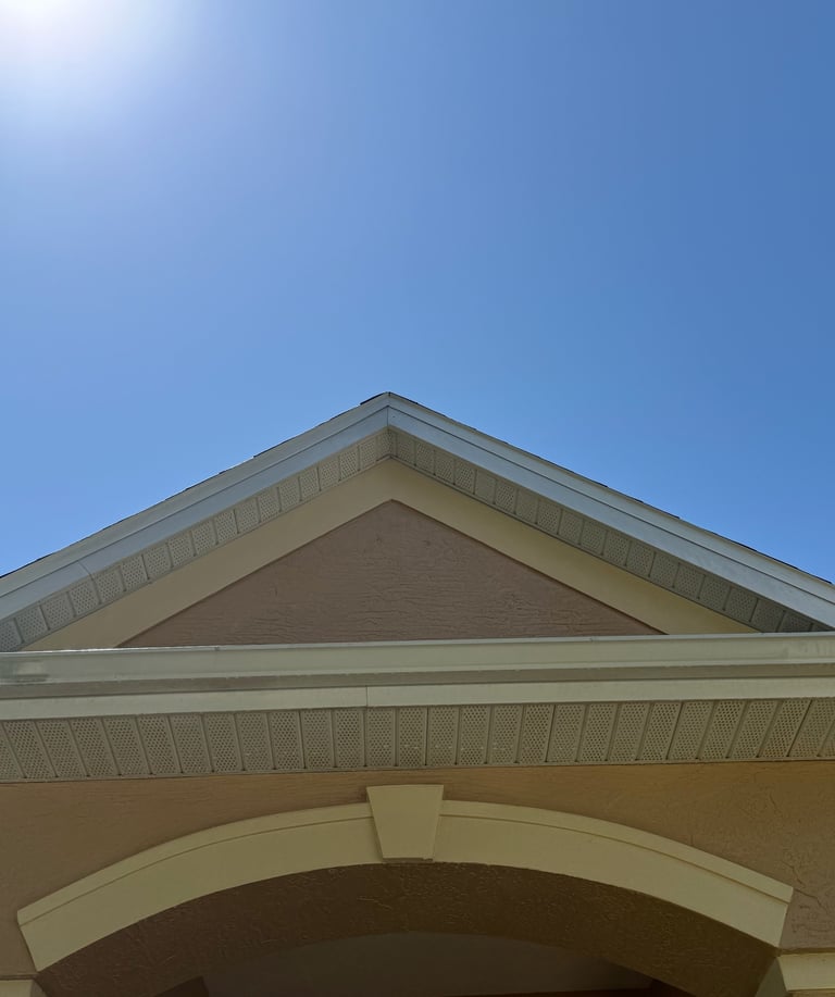 Cream-colored building roof and arched entryway against a clear blue sky